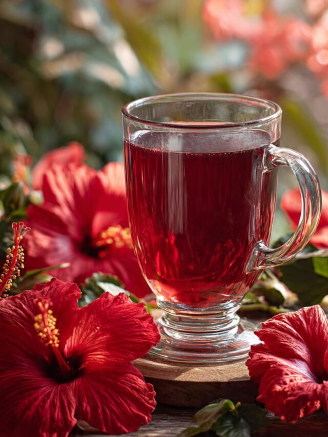 Fresh hibiscus tea in a glass cup surrounded by hibiscus flowers, symbolizing health and wellness benefits